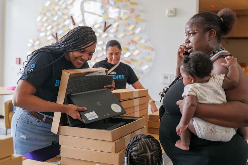 A family from southern Dallas receives a laptop from AT&T volunteers Tonia Lott (foreground,...