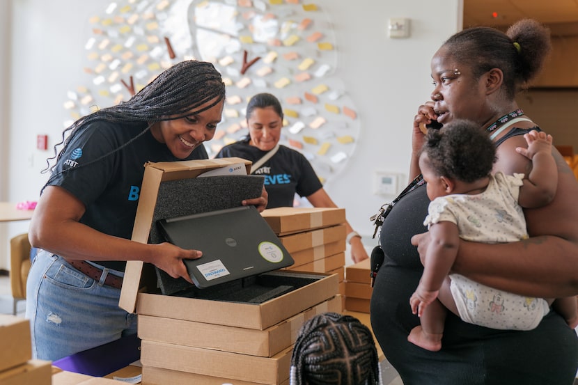 A family from southern Dallas receives a laptop from AT&T volunteers Tonia Lott (foreground,...