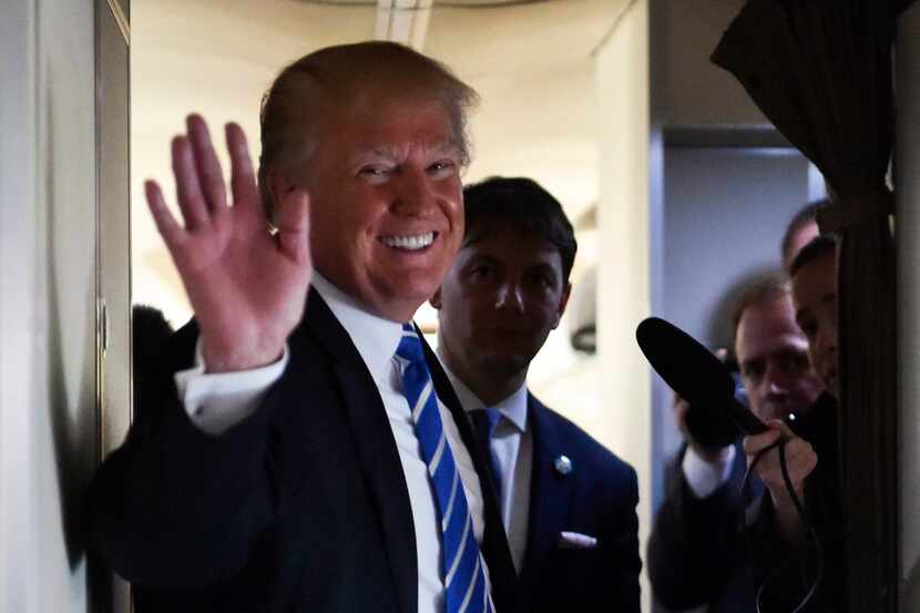 President Donald Trump waves as he speaks to reporters on board Air Force One as he travels...