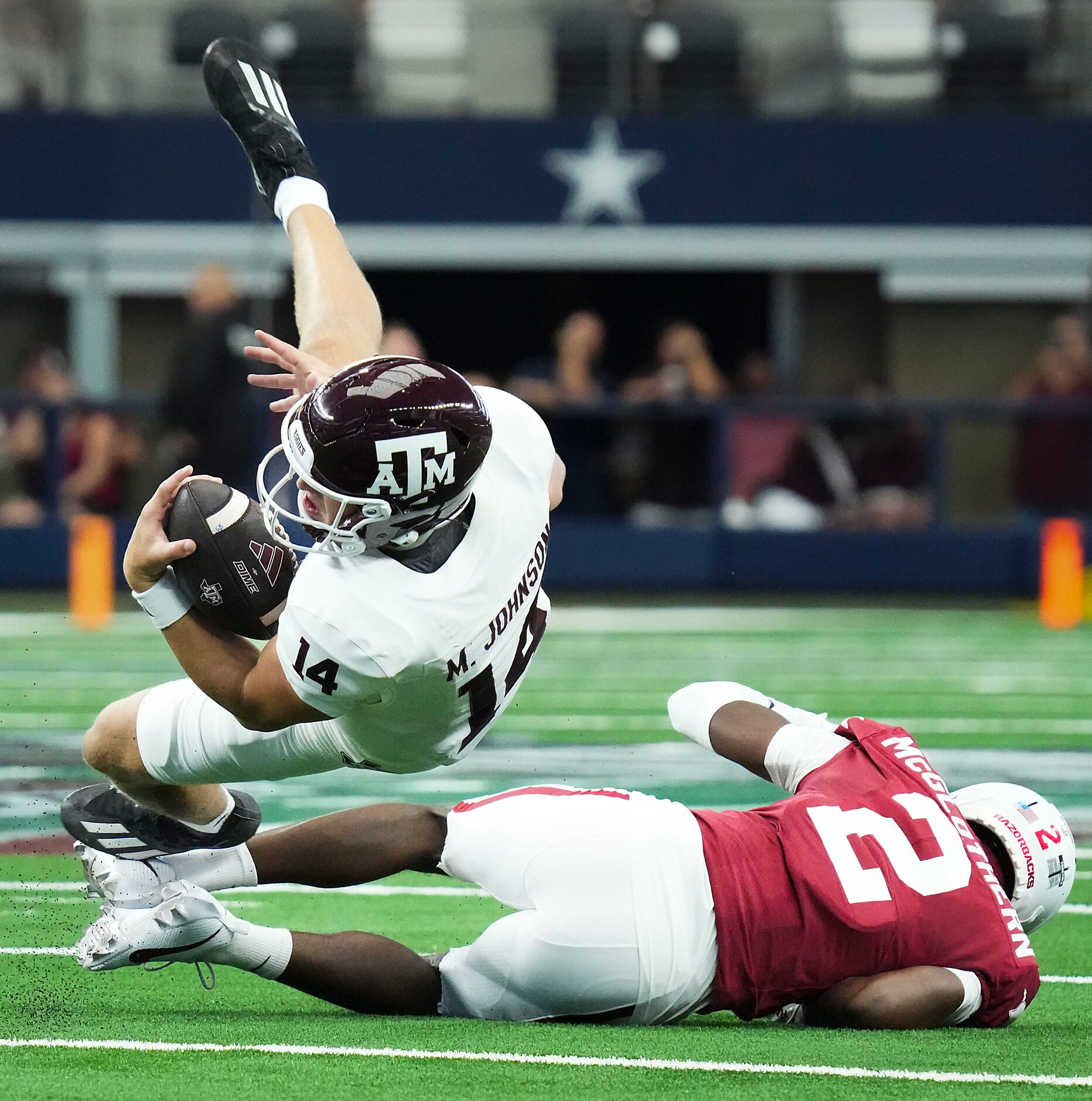 Texas A&M quarterback Max Johnson (14) is upended by Arkansas defensive back Dwight...