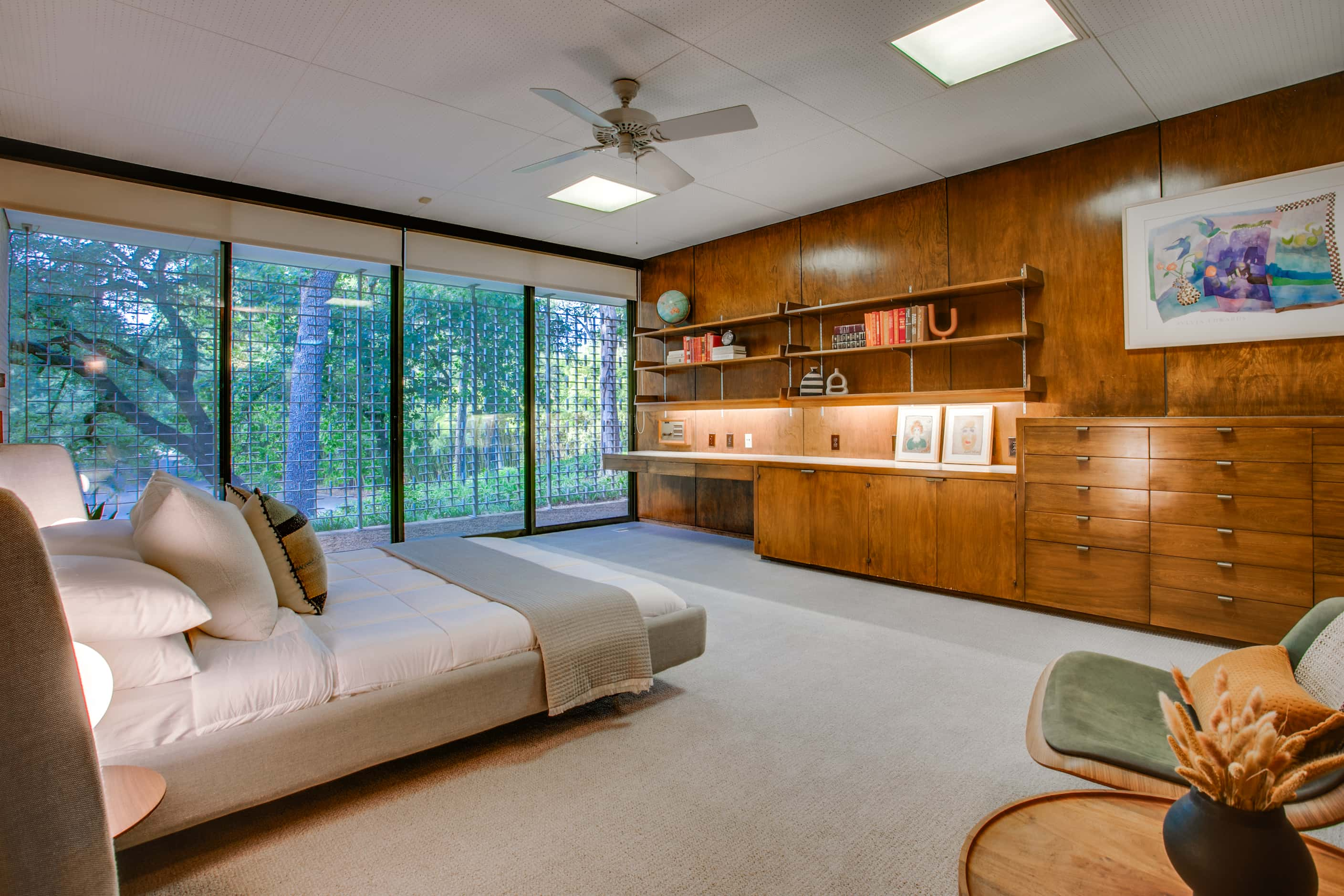 Bedroom with low platform bed, built in cabinetry and desk space, large windows