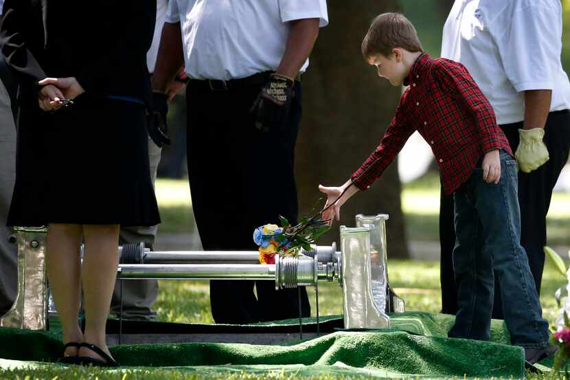 Magnus Ahrens, 8, son of fallen Dallas police officer Lorne Ahrens, drops flowers inside his...