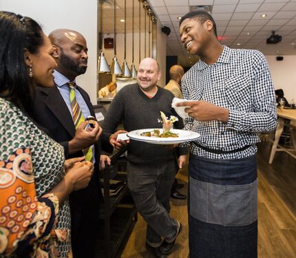 Intern Malik Runnels (right) of Pleasant Grove serves hors d'oeuvres at Cafe Momentum's...