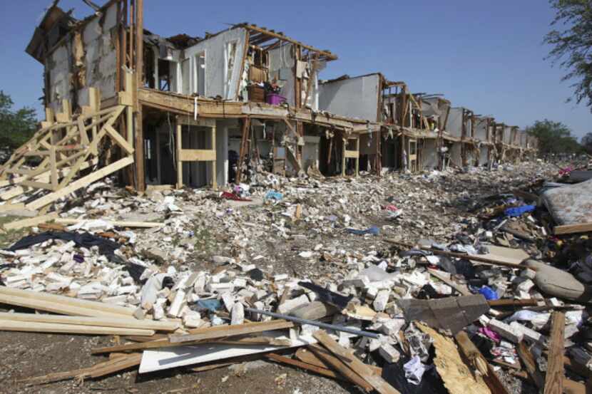 Debris litters the ground outside a destroyed apartment complex next to the site of the...