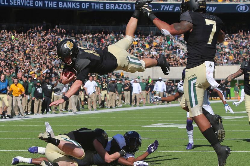 Baylor quarterback Charlie Brewer, center, dives over the goal line for a touchdown in the...