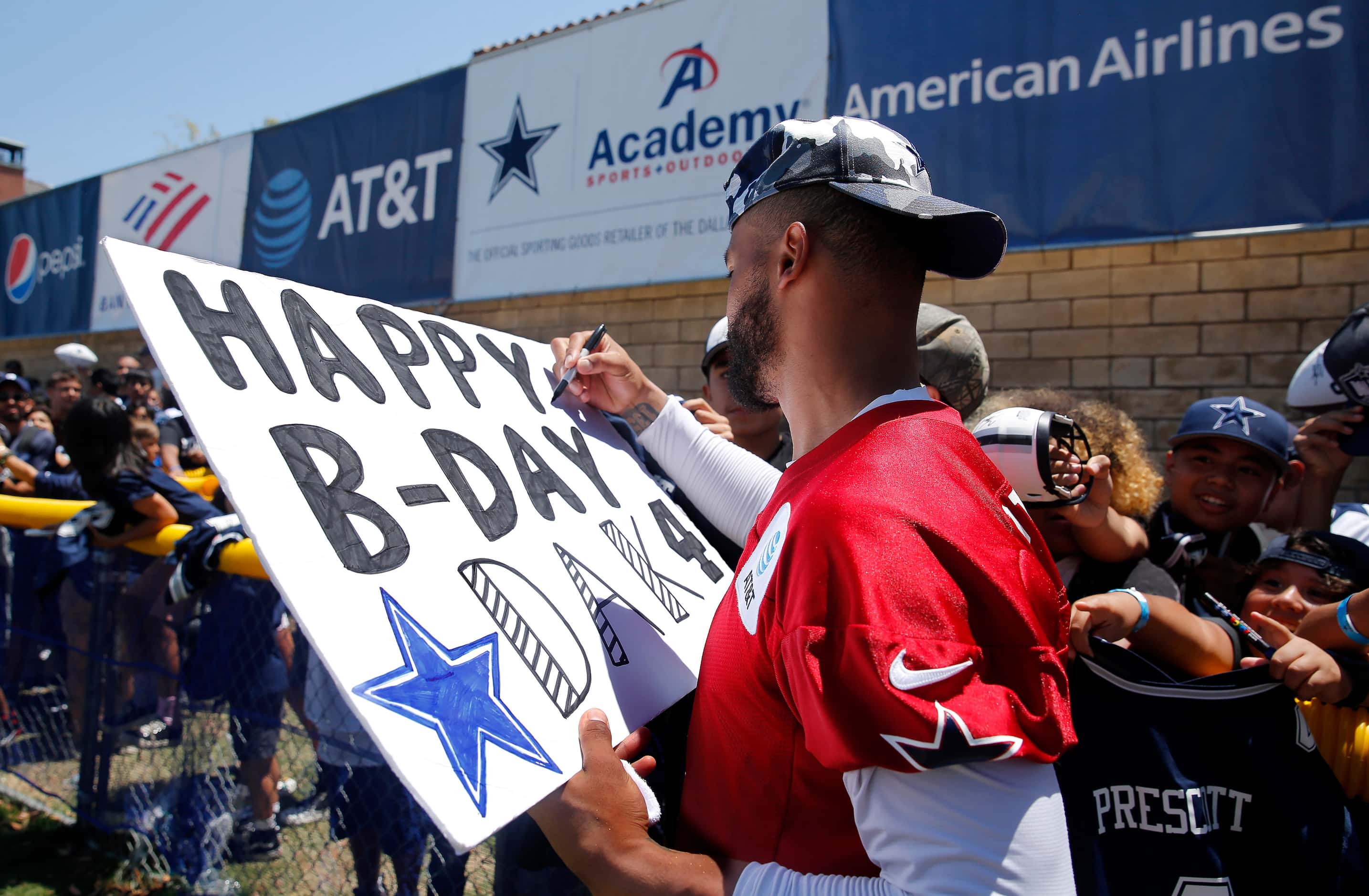 Dallas Cowboys quarterback Dak Prescott (4) signs a Happy Birthday placard for kids...
