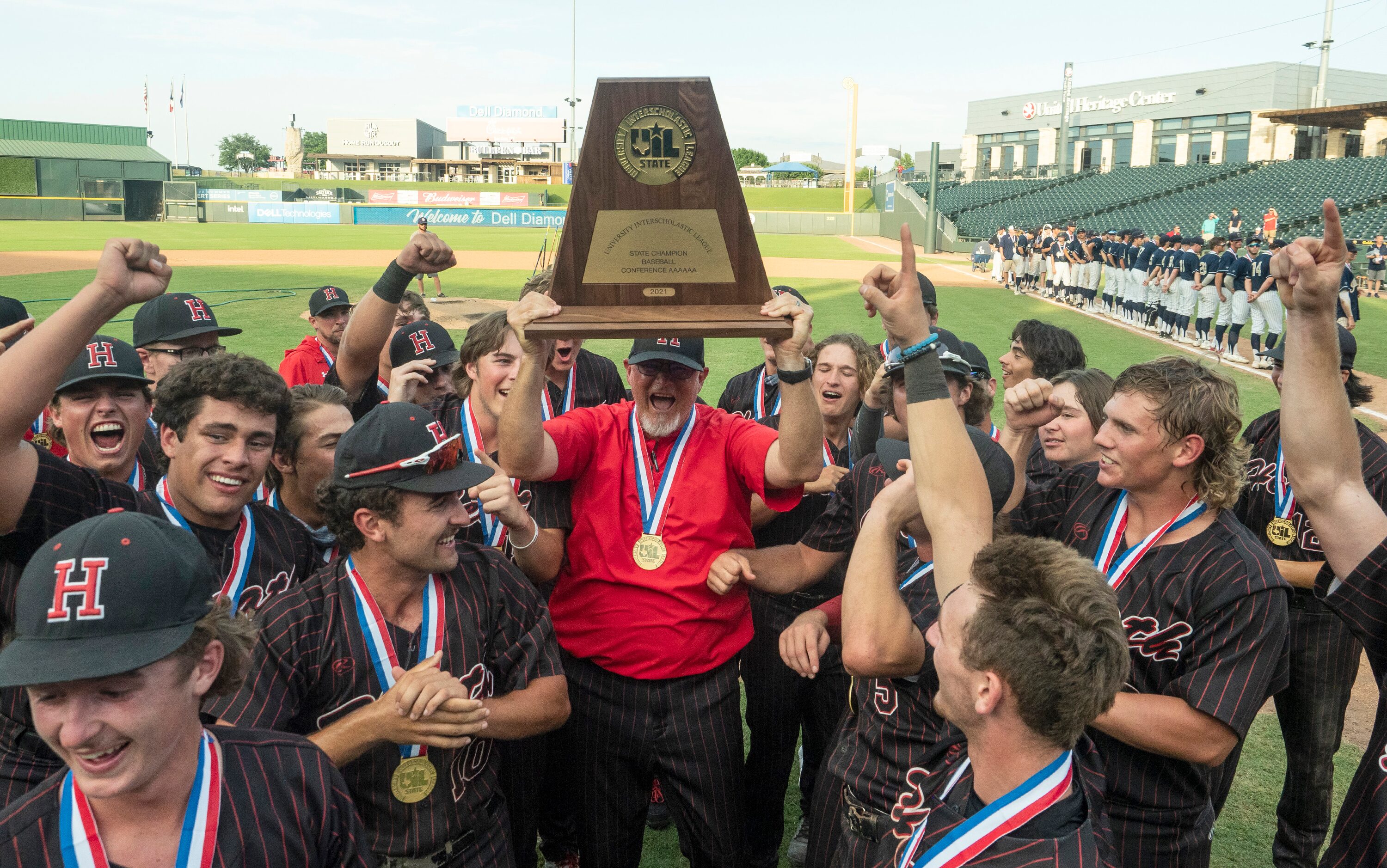 Rockwall-Heath head coach, Greg Harvey and the team celebrate with the championship trophy...