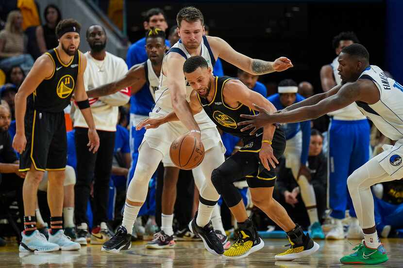 Dallas Mavericks guard Luka Doncic (77) tries to steal the ball from Golden State Warriors...
