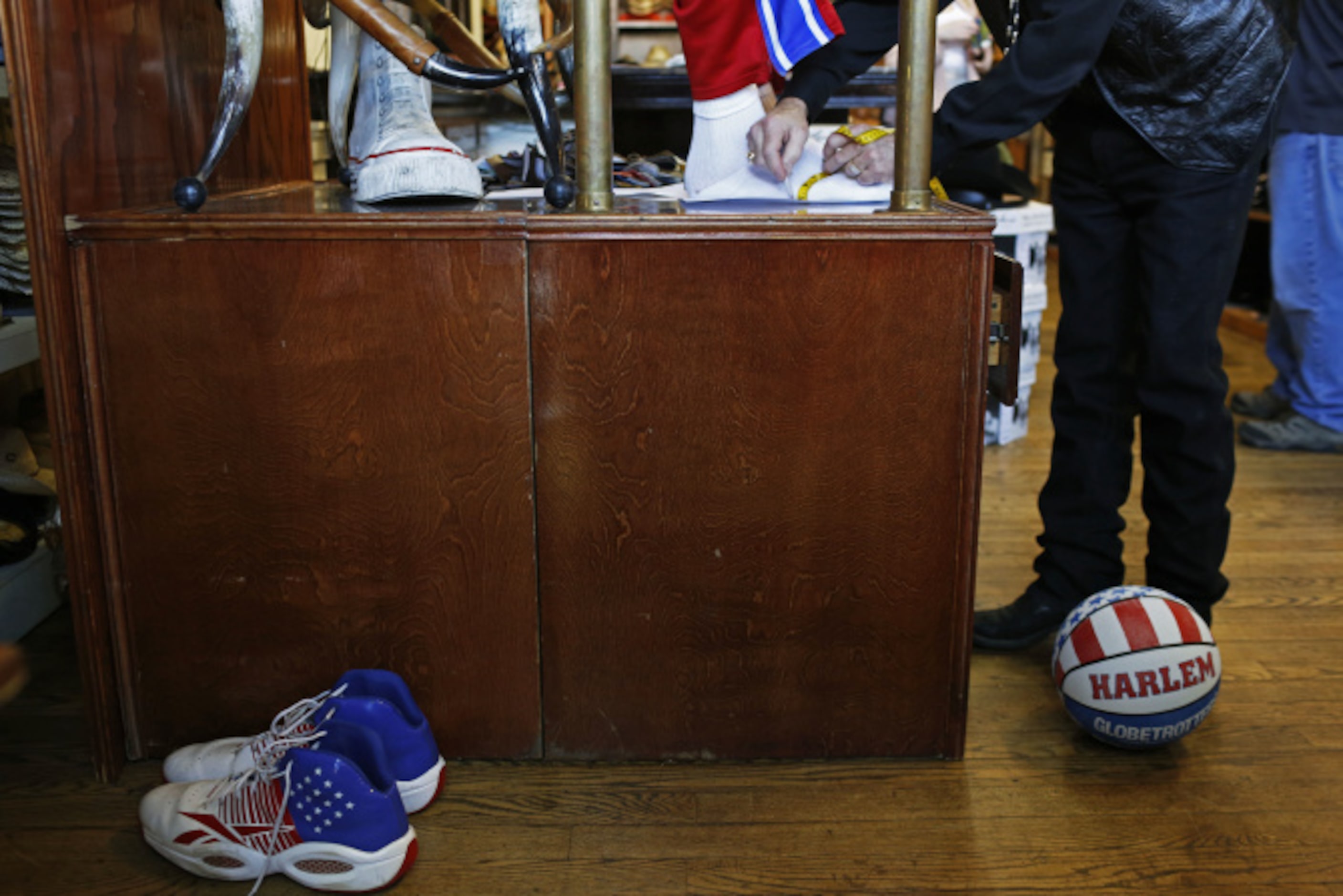 Harlem Globetrotter Paul "Tiny" Sturgess gets his feet measured by store owner Bill Dewbre...