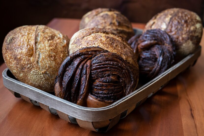 A basket of Chocolate Babka bread, bottom-center, and Sourdough Blue Tinge Emmer, from Lucia...