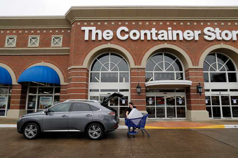 An employee at The Container Store loads an order for a customer waiting in the curbside...