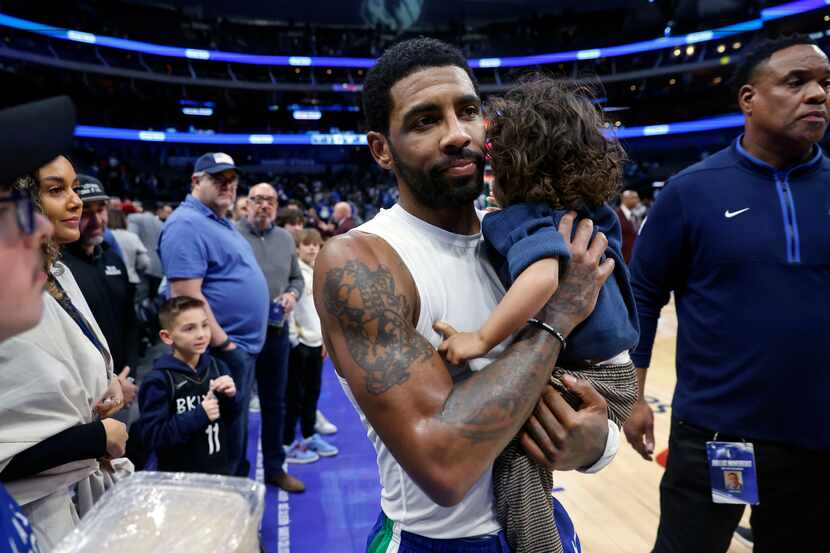 Dallas Mavericks guard Kyrie Irving carries his son Kaire to the locker room following their...