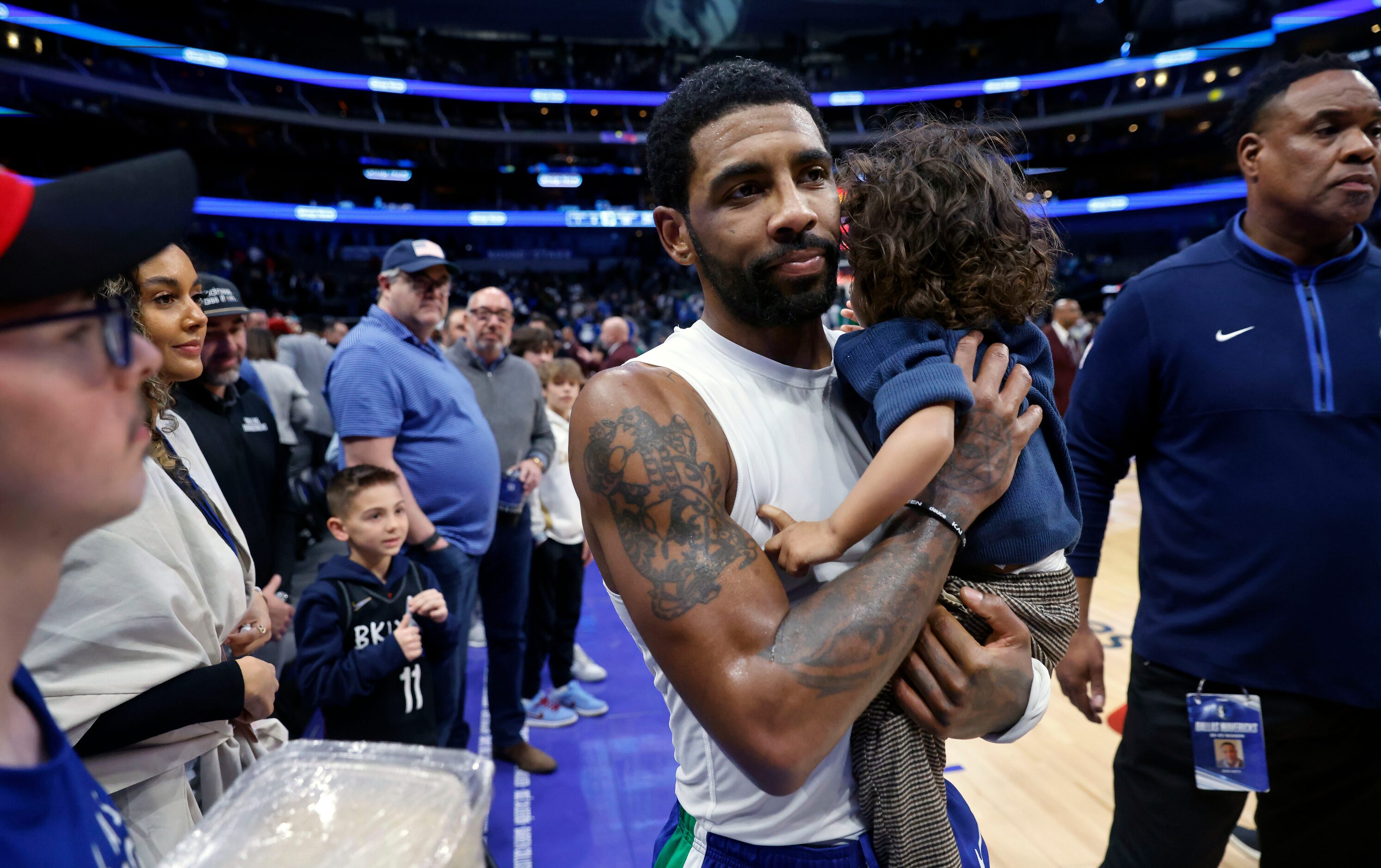 Dallas Mavericks guard Kyrie Irving caries his son Kaire to the locker room following their...