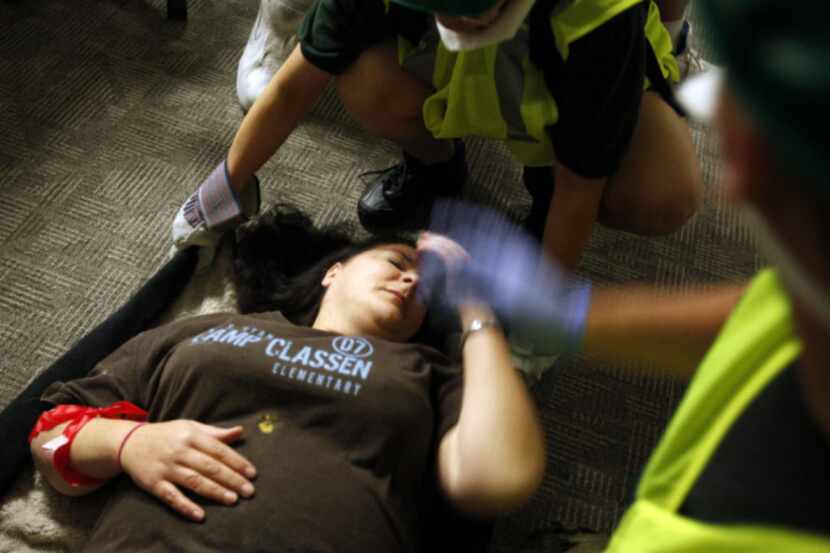 Carole Novielli, acting as an injured victim in a simulated tornado disaster, is assisted by...