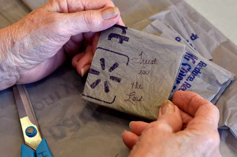 Volunteer Marilyn Hamilton, 78, writes phrases such as "Trust in the Lord" on pieces of the...