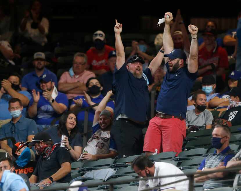 A fan celebrates after catching a foul ball in the stands during the second inning of game...