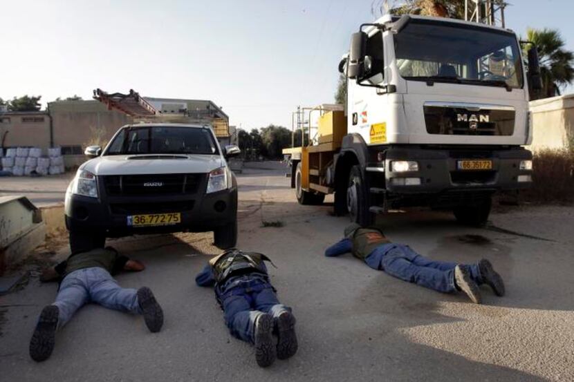 
Workers with the Israel Electric company took cover Monday near the Israel-Gaza border...