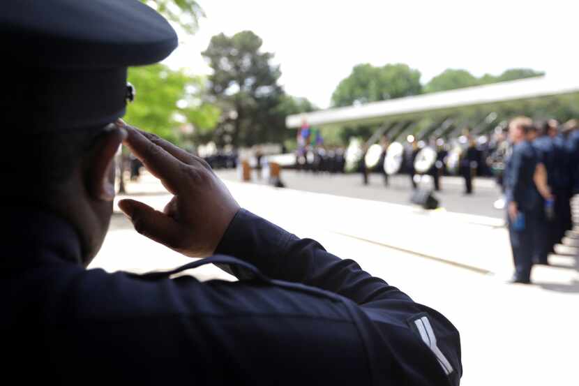 Police salute during a march and ceremony near City Hall in downtown Dallas. 