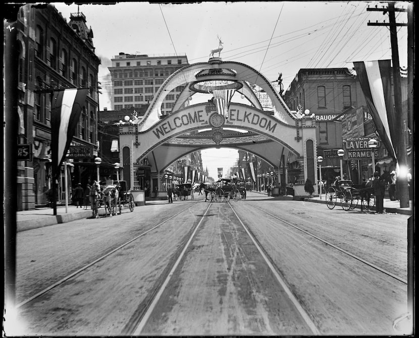 Horses and buggies and the Elks Arch of Honor reading Welcome Elkdom, on Main Street looking...