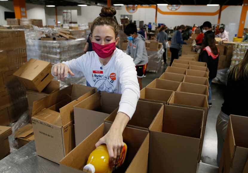La voluntaria Heather Rey of Plano ayuda a llenar cajas de comida para distribuir entre...