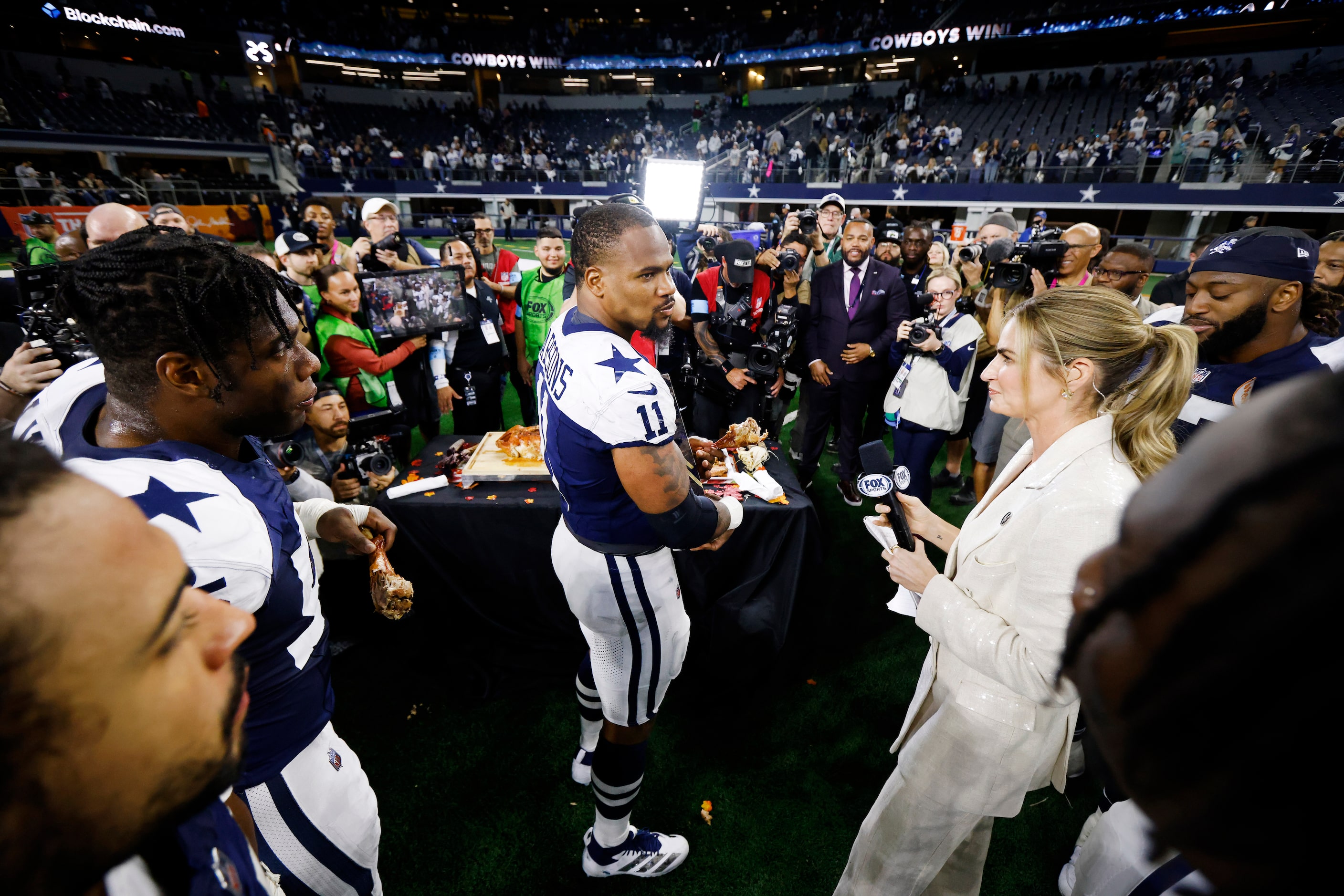 Dallas Cowboys linebacker Micah Parsons (11) takes a bite fro ma turkey leg as he and the...