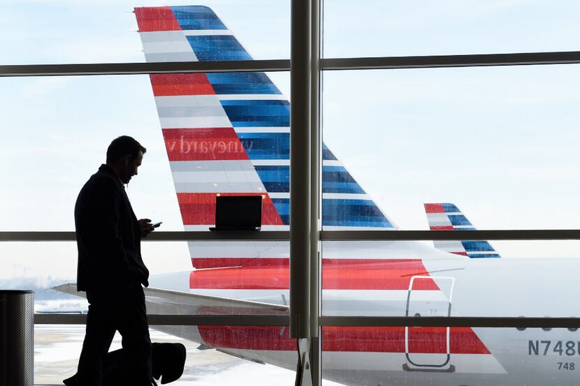 In this Jan. 25, 2016, file photo, a passenger talks on the phone as American Airlines jets...