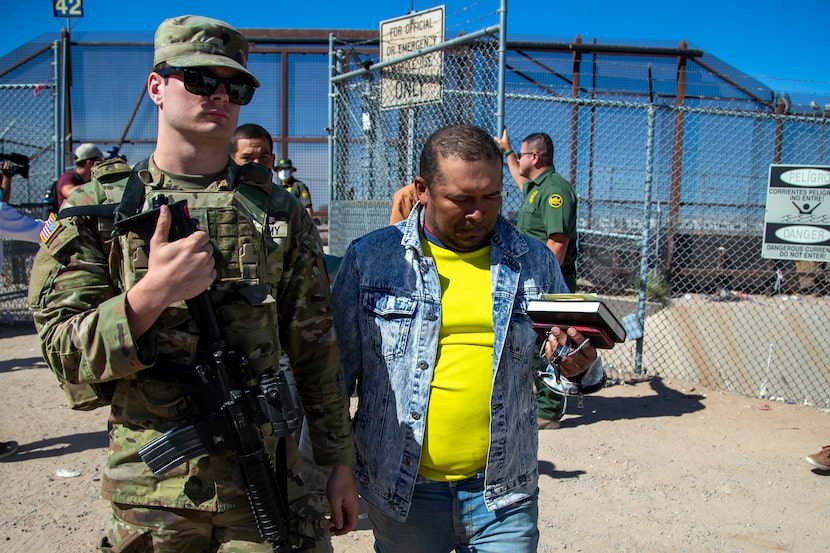 FILE - Migrants are escorted by a U.S. Army soldier after entering into El Paso, Texas from...