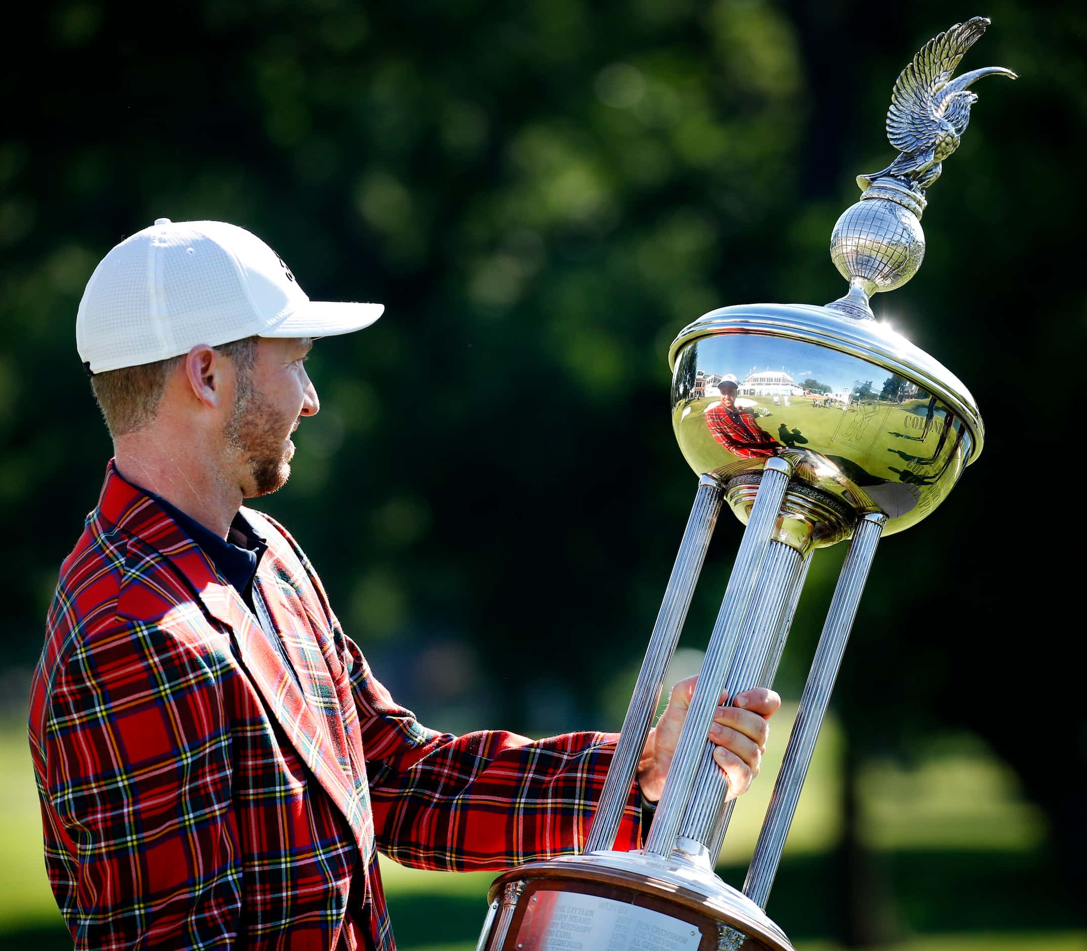 On the 18th green, PGA Tour golfer Daniel Berger looks at himself reflected in the winning...