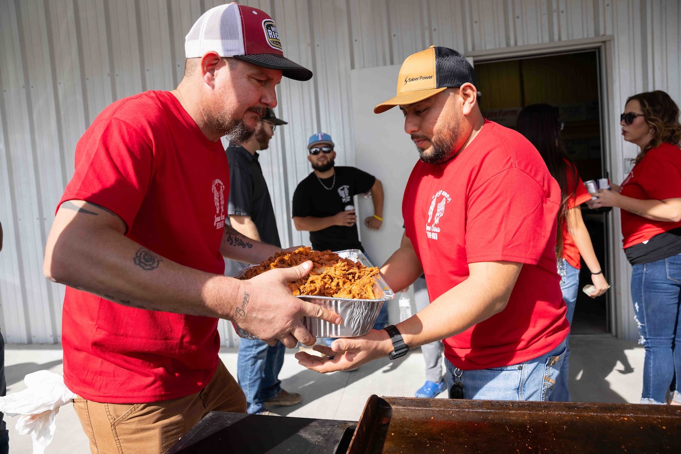 Walnut Springs mayor Sammy Ortega (left) hands Juan Jacquez freshly grilled trompo meat as...