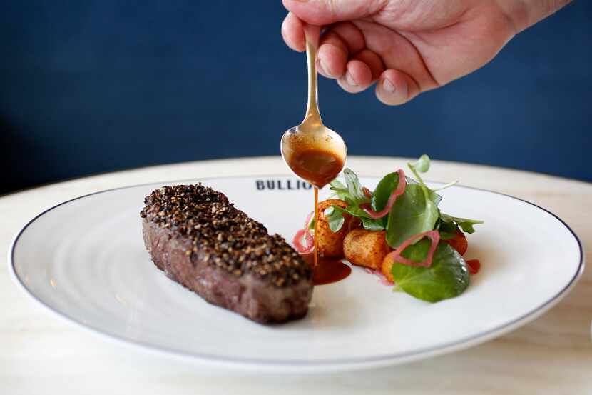 Chef Bruno Davaillon pours sauce on the Bison Au Poivre, photographed at Bullion in 2018....