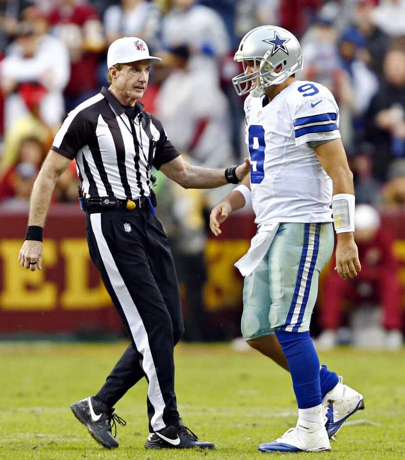 A game official rushes over to check on Dallas Cowboys quarterback Tony Romo, seemingly in...