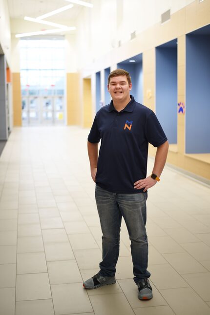 Luke of McKinney High School poses in his school's hallway in a blue McKinney marching band...