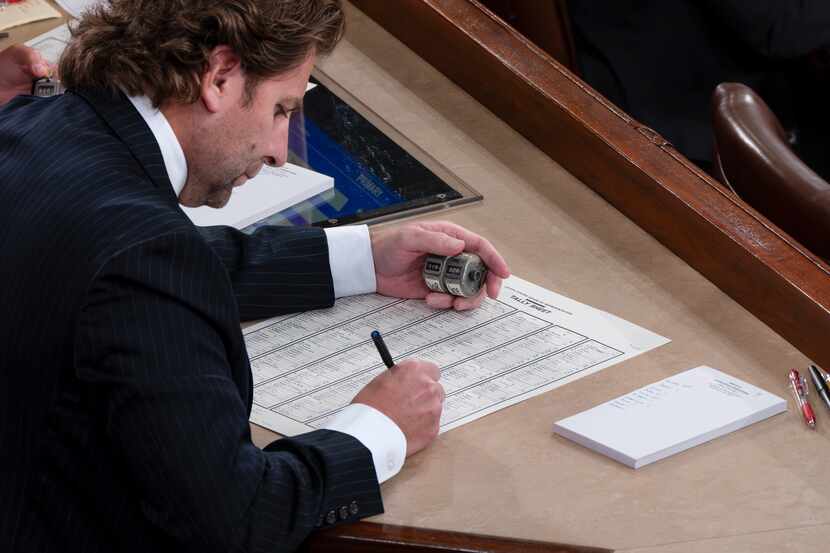 A clerk uses a sheet listing all the members of the House of Representatives and an...