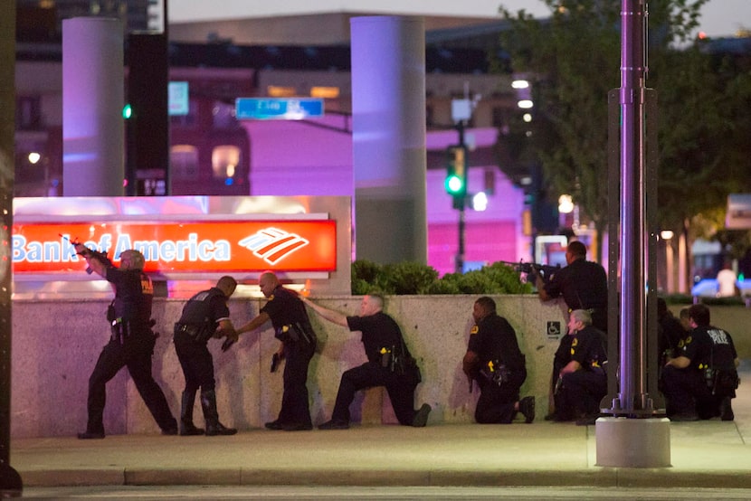 Dallas police take up positions along a wall at the corner of Lamar and Main streets as they...