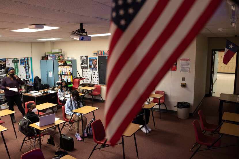 Una bandera estadounidense flamea en una clase de historia americana en un aula de octavo...
