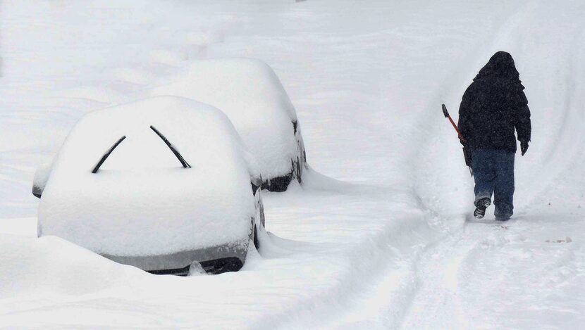  A man walks with his snow shovel down Woodlawn Ave. in Beckley, W.Va. Saturday afternoon,...