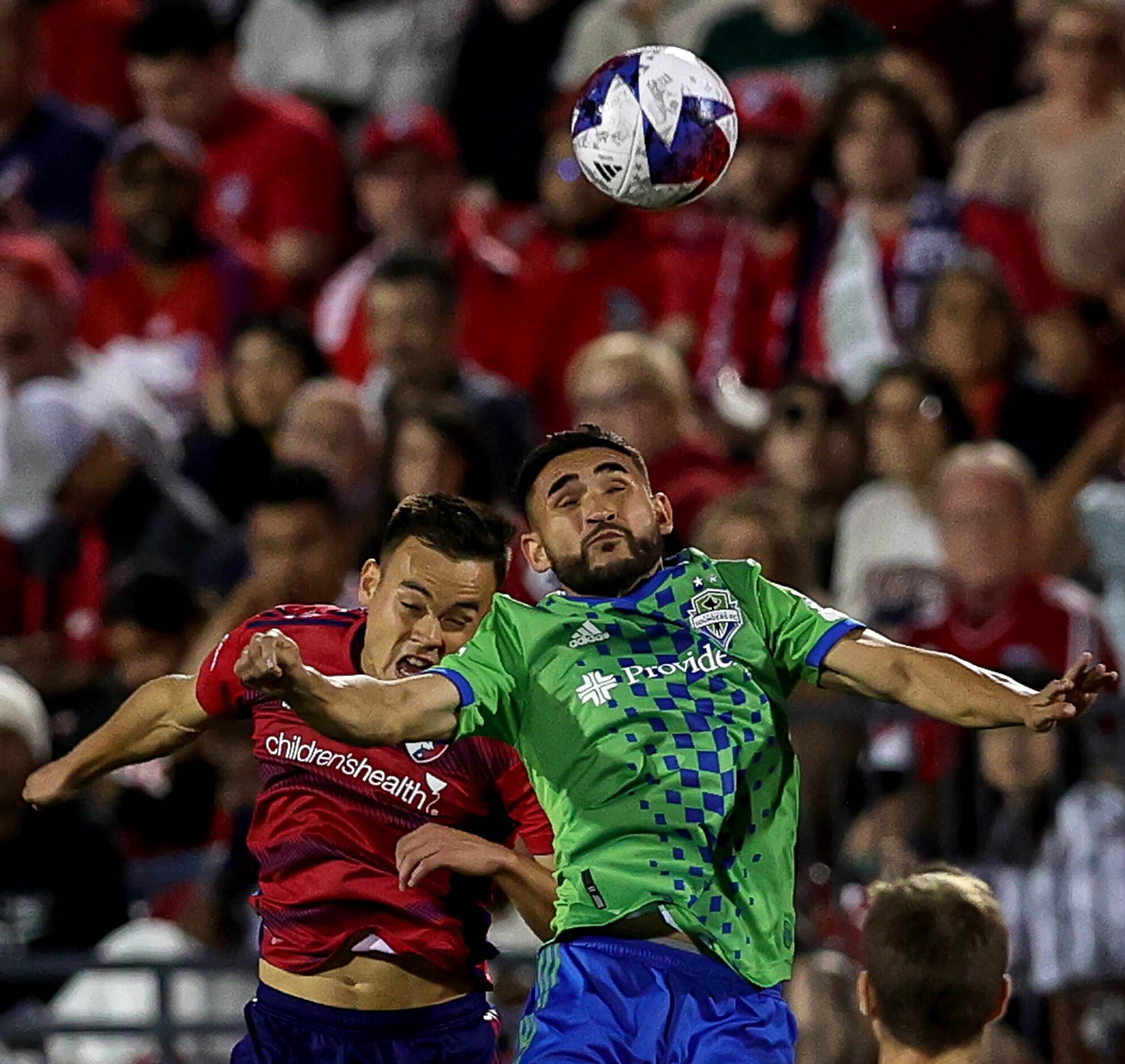 Seattle midfielder Cristian Roldan (right) heads the ball away from FC Dallas defender Sam...