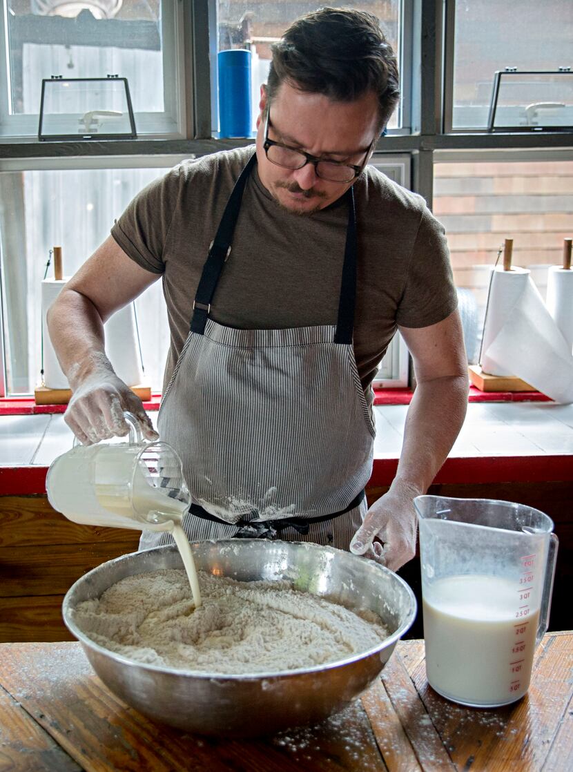 Chef Tim Byres adds heavy cream dry ingredients as he prepares buttermilk biscuits at...