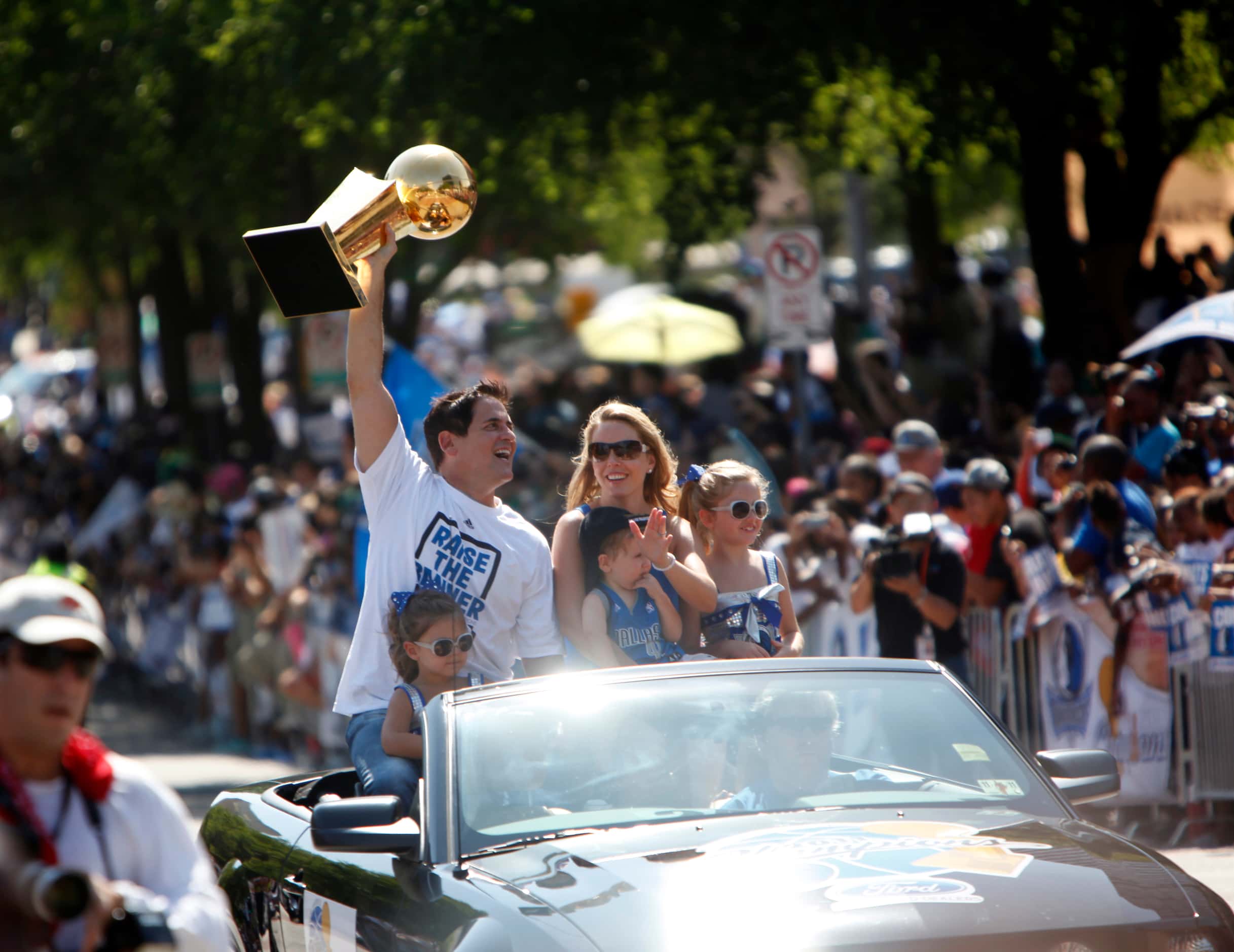 Accompanied by his family Dallas Mavericks owner Mark Cuban hoists the Larry O'Brien NBA...