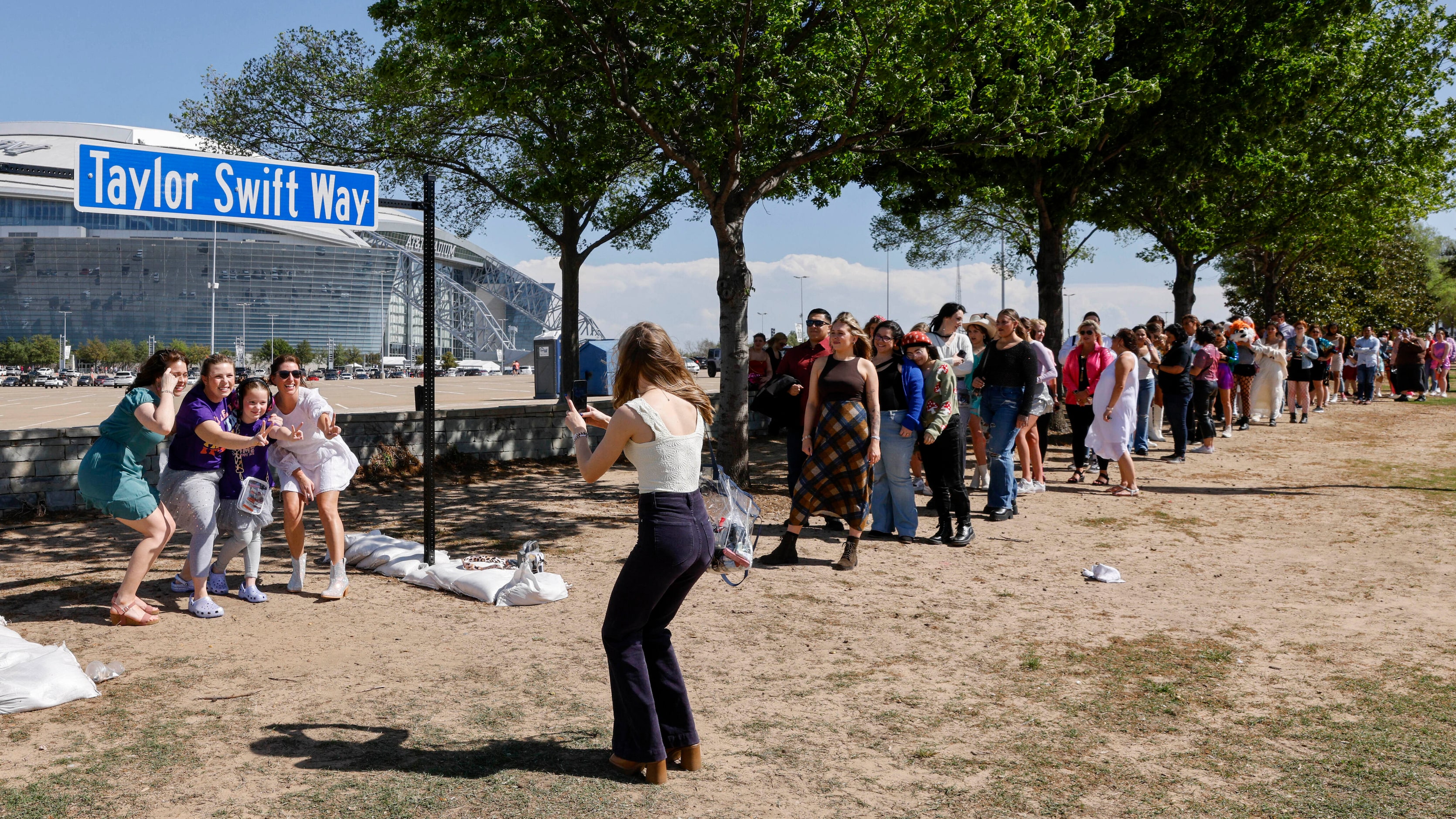 Fans pose for photos with a “Taylor Swift Way” street sign before a Taylor Swift Eras Tour...