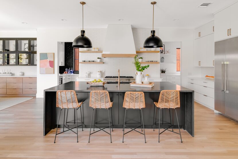 A modern kitchen features white paint and a black island.