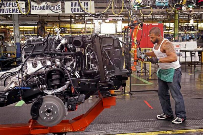 General Motors worker Stephen Carpenter assembles an outside temperature gauge for a new SUV...