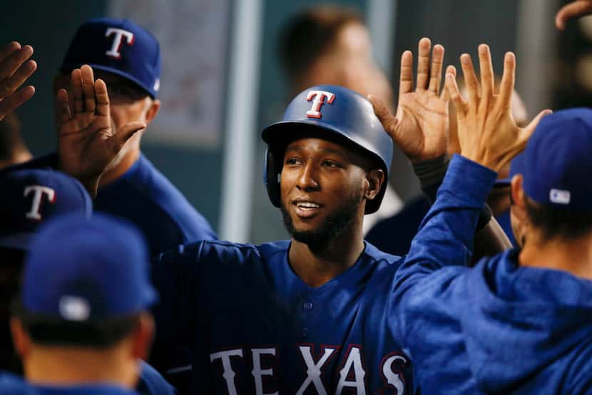 Texas Rangers' Jurickson Profar, center, is greeted by teammates in the dugout after he...