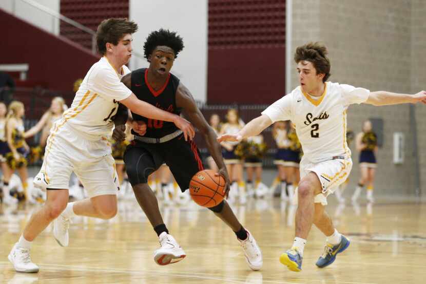 Irving MacArthur's Andrew Jones (10) drives between Highland Park's Ethan Nussbaum (14) and...