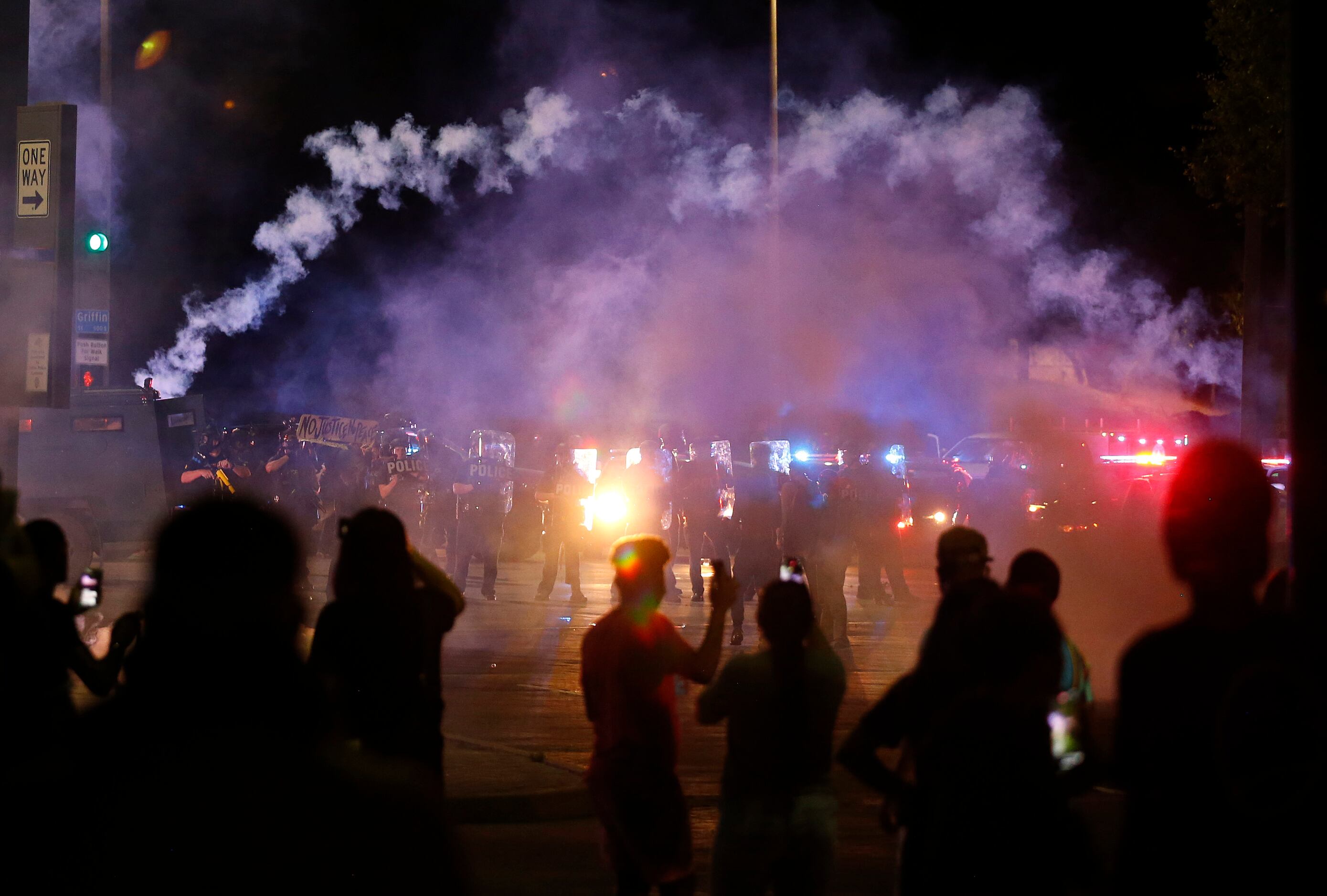 Tear gas canisters fly as Dallas police attempt to disperse the crowd along Young Street and...