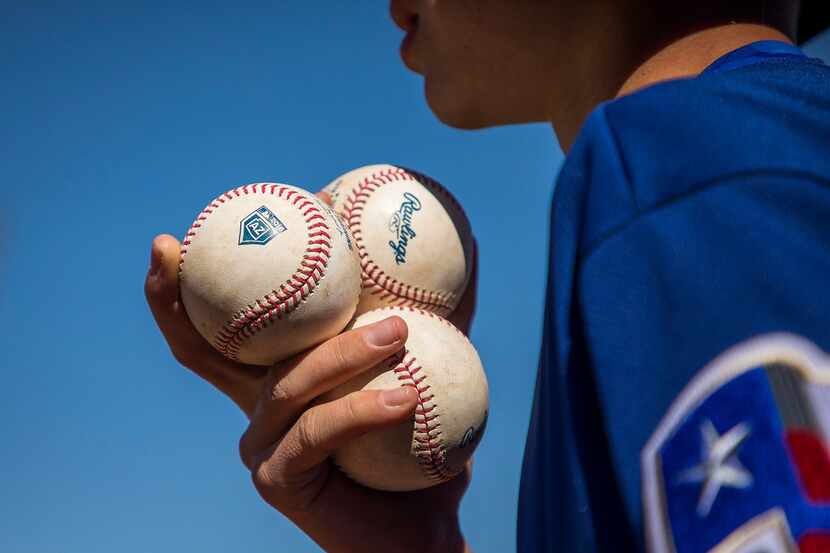 A ballboy takes a fresh set of balls out to the home plate umpire djuring a spring training...