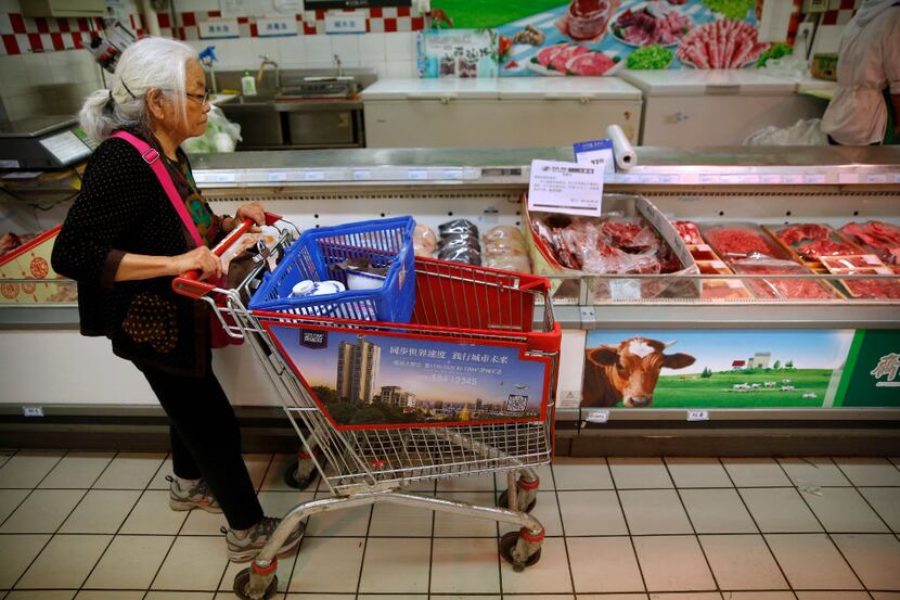 A woman pushes her shopping cart past a display of domestically produced Chinese beef at a...