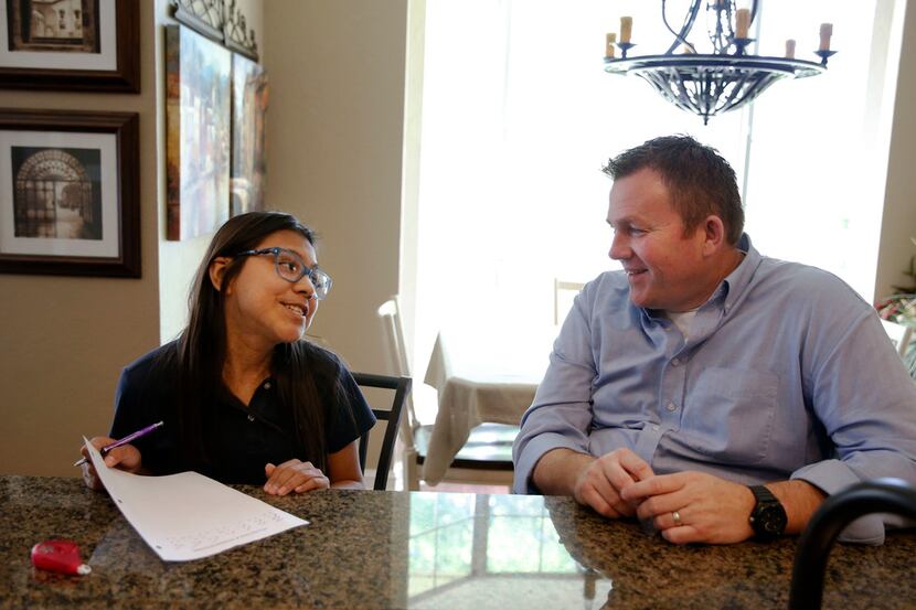 Jason Ballard helps his 12-year-old adoptive daughter, Emi, with math homework at their home...