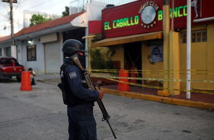 A police officer guards the scene outside a bar where more than 20 people died in an...