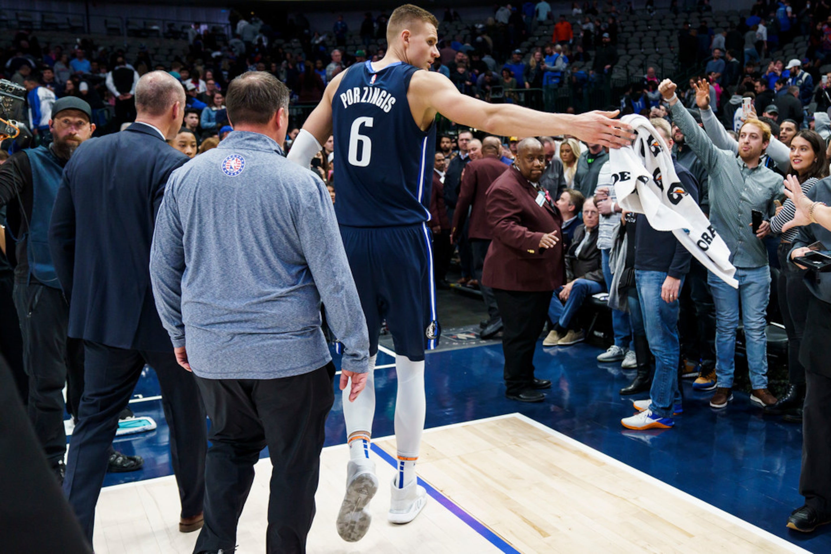 Dallas Mavericks forward Kristaps Porzingis tosses a towel to the crowd as he leaves the...